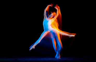 Fototapeta na wymiar Dynamic portrait of tender slim girl, female ballet dancer in art performance isolated over black background in mixed bright neon light.