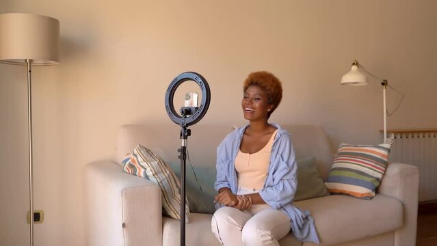 influencer content creating Beautiful young woman looking at phone screen and recording video using cell phone and tripod and round lamp lighting for video recording for social networks. Video footage
