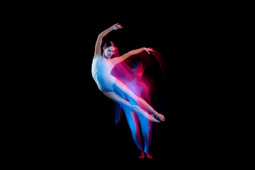 Graceful ballerina dancing on dark background in mixed neon light. Grace, movement, action and...