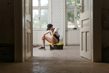 Tired and frustrated women resting during home renovation work, taking a break during DIY home...