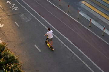 Man is riding on kick scooter on cycling road. Top aerial view.