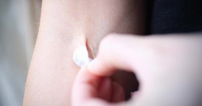 A woman removes a round patch from her hand