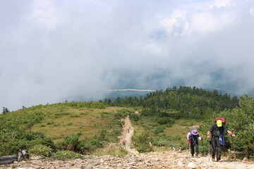 Obraz premium Mountain Hiking Trail on a Foggy Ridge with Adventurers