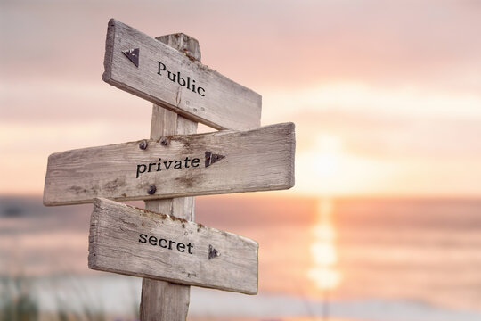 public private secret text quote engraved on wooden signpost outdoors on the beach with sunset theme.