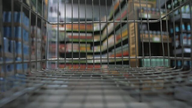 Emty Cart In Supermarket Driving By Buyer Along Food And Products Showcase Rows. Shopping Trolley In A Store. POV, Time Lapse, Blurred Shot.