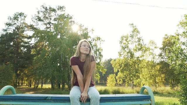 Bored woman sitting on bench feels lonely and unhappy. Girl missing someone for a date. Unpleasant thoughts, suffering due brake up, bad romance and personal life troubles. 