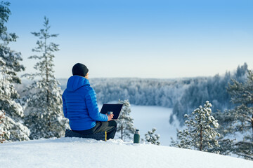 Winter freelance. Man with laptop and thermos working outdoor in winter.