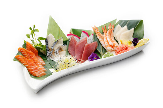 Sashimi sushi set with raw fishes on banana leaves, isolated on white background. Packshot for restaurant menu.