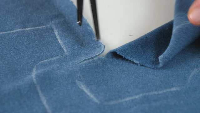 Dressmaker Cutting And Following The Outline Markings On The Fabric With A Scissors. - close up