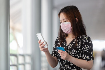 young adult asian woman with surgical face mask shopping via online application media concept. 