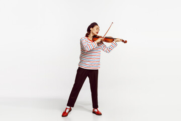 Portrait of beautiful young woman playing violin isolated over white studio background. Tender,...