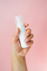 Blank white beauty product in female hands, skin care, healthy nails. Pink background