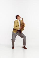 Portrait of young man in stylish yellow jacket playing saxophone isolated over white background. Jazz performer