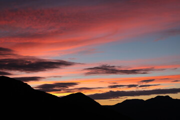 鮮やかでカラフルなグラデーションの朝焼けと山々のシルエット