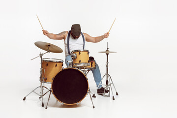 Portrait of emotive, expressive man in sunglasses playing drums, performing isolated over white background. Rock concert