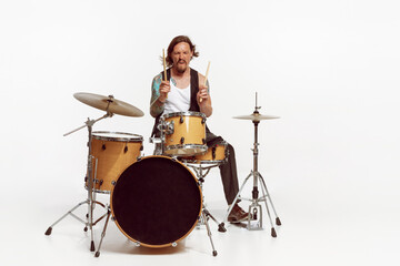 Portrait of young man playing drums, performing isolated over white studio background. Tattoo art...