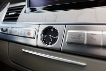 Mechanical clock mounted on the wooden center console of a car.