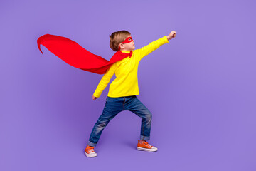 Full length photo of funky cool small son wear red mantle wind blowing rising fist isolated violet...