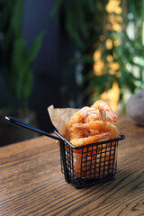 Panko tiger prawns. Fried shrimps in a metal serving basket, on a table, selective focus.