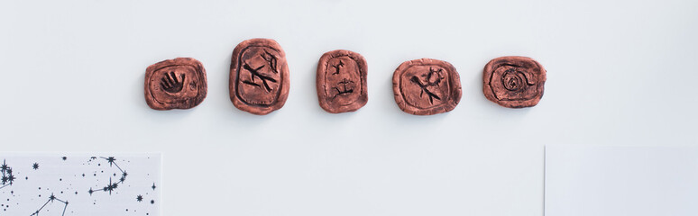 top view of clay runes near celestial charts on white surface, banner.