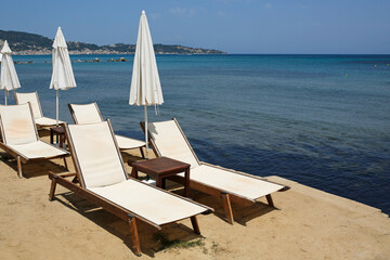 empty sunbeds and umbrellas by the sea on the greek island