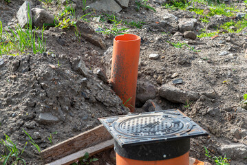 Inspection of the sewage system with a closed cast iron manhole, visible plastic pipes.
