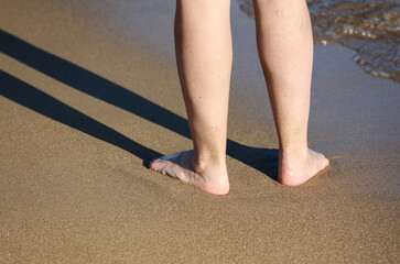 Legs of a woman on a sandy beach by the sea