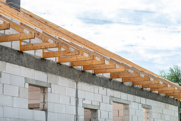 Roof trusses not covered with ceramic tiles on a single-family house under construction, visible roof elements and rafters.