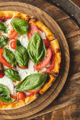 Appetizing pizza with tomatoes and cheese on a wooden background. Slice of pizza with stretchy cheese