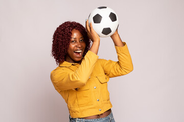 excited young black lady playing with a football