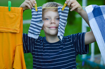 A happy caucasian 9 years boy helps her mother to hang up clothes. Development of fine motor skills...