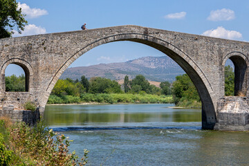 The Bridge of Arta. A stone bridge that crosses the Arachthos river  in the west of the city of Arta in Greece. Sunny summer day with blue sky