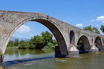 The Bridge of Arta. A stone bridge that crosses the Arachthos river  in the west of the city of Arta in Greece. Sunny summer day with blue sky