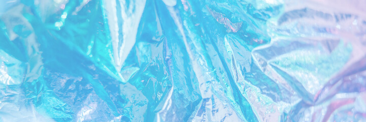 Iridescent foil texture background. Holographic wrinkled surface. Vibrant blue gradient template...