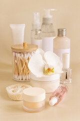 Fototapeta na wymiar Natural cosmetic jars and skin care accesories with white orchid flower on beige close up