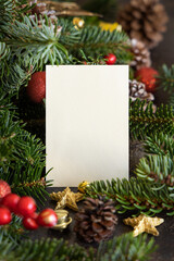 Vertical blank card between christmas decorations, fir branches and pine cones close up