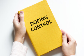 Doping Control inscription on the cover of a notebook on a light background in the hands of a doctor