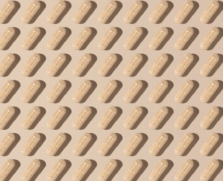 Creative pattern with capsules on light beige top view, hard shadows. Taking supplements