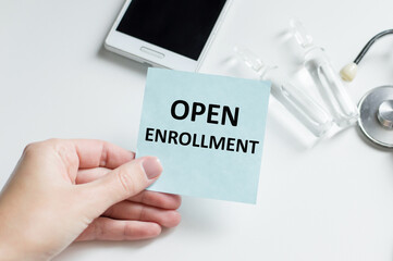 Doctor, man put a card with the text Open Enrollment. Medical concept.