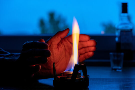 a man warmed his hands from an alcohol lamp in the absence of heating concept of the energy crisis in Europe caused by the rejection of fossil fuels. Blackout