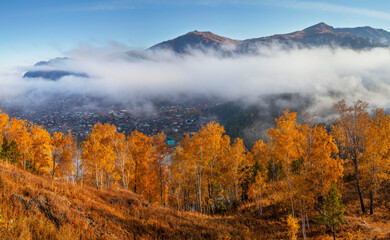Autumn view, Altai nature. Fog above the mountain valley, the village below.