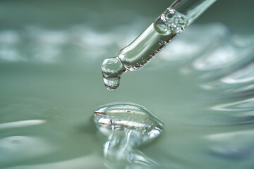 Dropper with serum or cosmetic oil on a green background.
