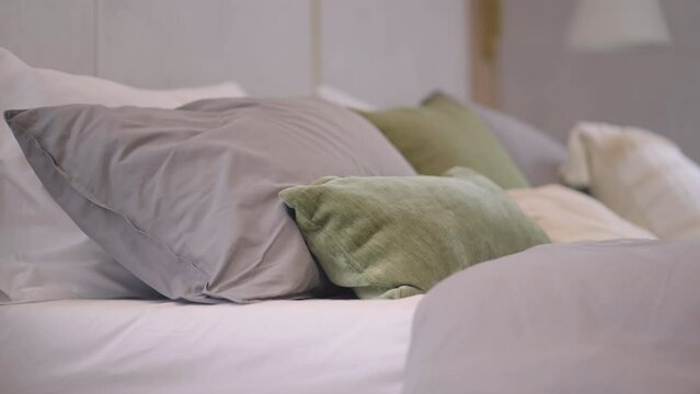 dolly shot of close up soft pillow arrange set on king size bed with nature sun light from window,bedroom pillow house design interior ideas background of contemporary home decorative detail