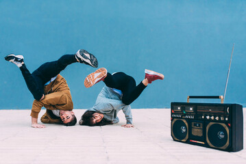 Young happy couple dancing on the street with a vintage radio cassette stereo .