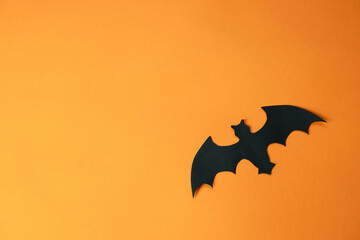 black bats made of colored paper on an orange background , a creative Halloween concept