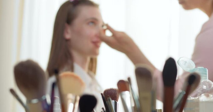 Makeup artist makes face makeup to beautiful young woman model. Cosmetics concept. Making mua.