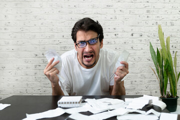 Close up of unhappy man sitting at the table, stressed and confused by calculate expense from...