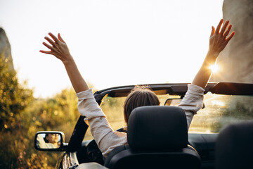 Woman sitting in car cabriolet and waving hands