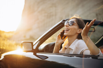 Woman road tripping by her car cabriolet