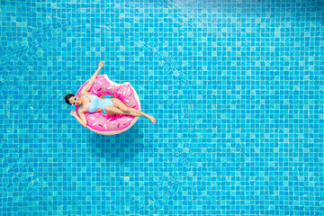 Top view of young asian woman in swimsuit on the pink donut lilo in the swimming pool. - 529442059